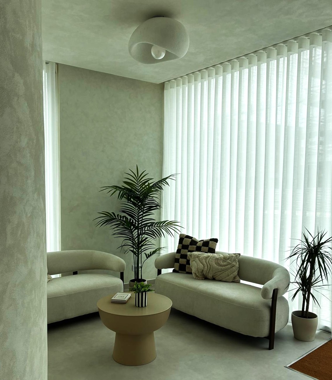 Receção da clínica The Journey MedSpa com sofás verdes claros, cortinados em linho e plantas naturais